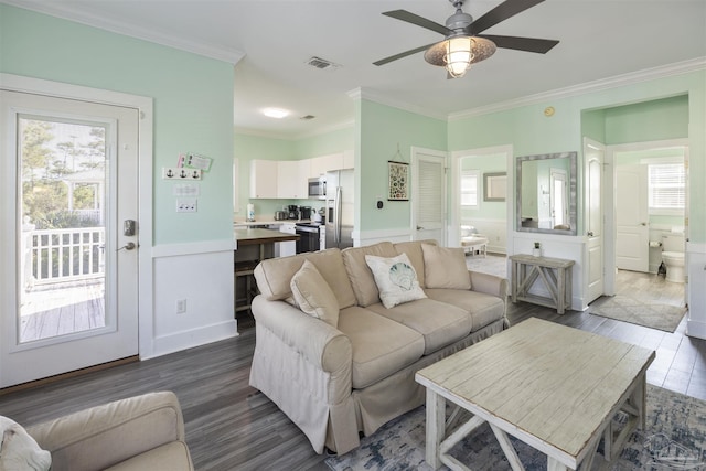 living room featuring wood finished floors, a ceiling fan, crown molding, wainscoting, and a decorative wall
