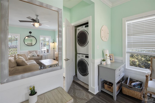 laundry room featuring stacked washer and clothes dryer, ornamental molding, a ceiling fan, wainscoting, and dark wood finished floors