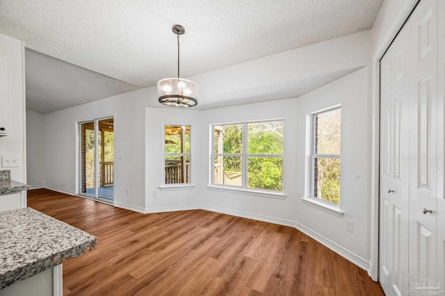 dining area with light wood-style flooring, a textured ceiling, and baseboards