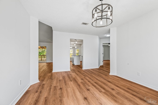 unfurnished dining area featuring visible vents, light wood-style flooring, ceiling fan with notable chandelier, and baseboards