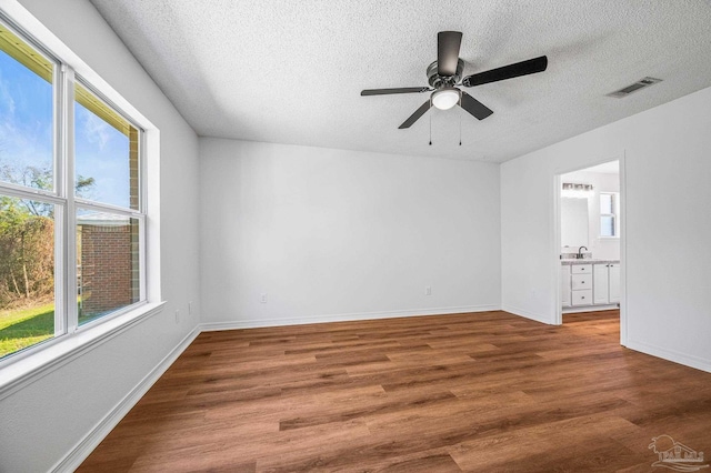 spare room with visible vents, a textured ceiling, baseboards, and wood finished floors