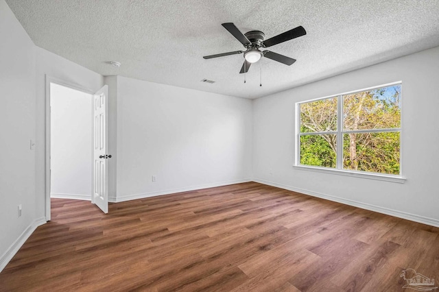 spare room featuring baseboards, a textured ceiling, and wood finished floors