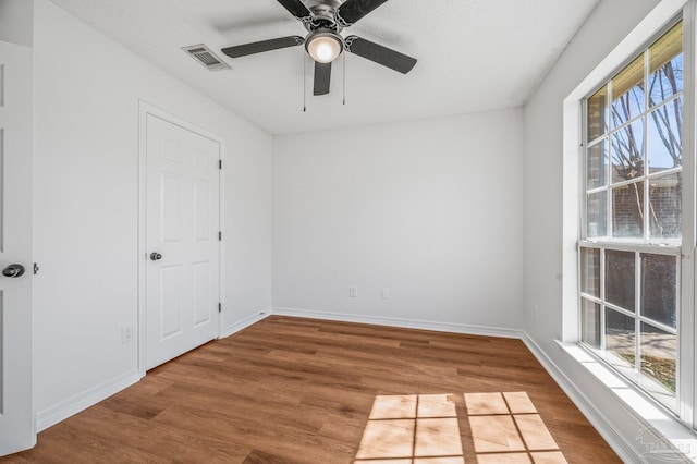 spare room with visible vents, baseboards, and wood finished floors