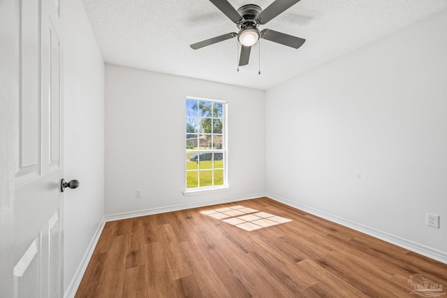 spare room with ceiling fan, a textured ceiling, baseboards, and wood finished floors