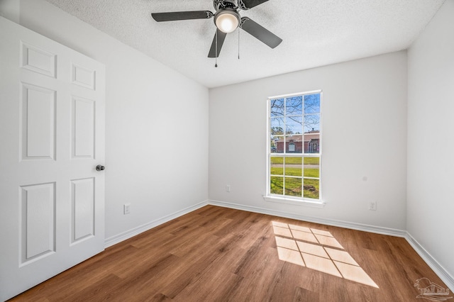 unfurnished room with ceiling fan, wood finished floors, baseboards, and a textured ceiling