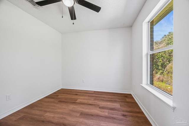 unfurnished room with dark wood finished floors, plenty of natural light, and baseboards