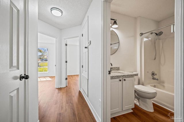 full bathroom featuring toilet, vanity, bathtub / shower combination, wood finished floors, and a textured ceiling