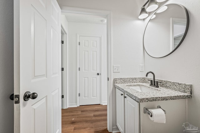 bathroom with vanity, wood finished floors, and baseboards