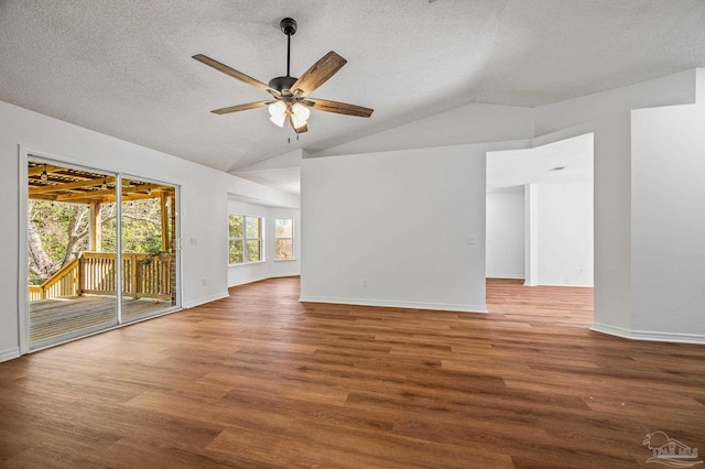 empty room featuring a textured ceiling, a ceiling fan, lofted ceiling, and wood finished floors