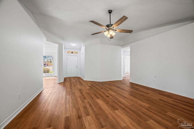 interior space featuring a textured ceiling, a ceiling fan, baseboards, and wood finished floors