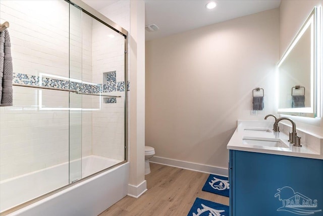 8169 White Sands Blvd, Navarre Beach, FL 32566 - full bathroom featuring toilet, wood finished floors, shower / bath combination with glass door, double vanity, and baseboards