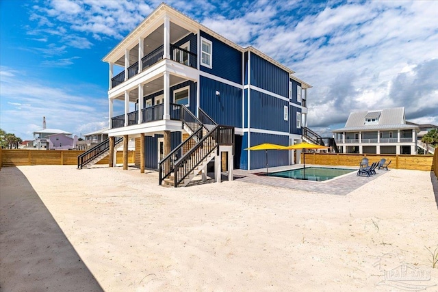 8169 White Sands Blvd, Navarre Beach, FL 32566 - rear view of property with stairs, a balcony, an outdoor pool, and a patio