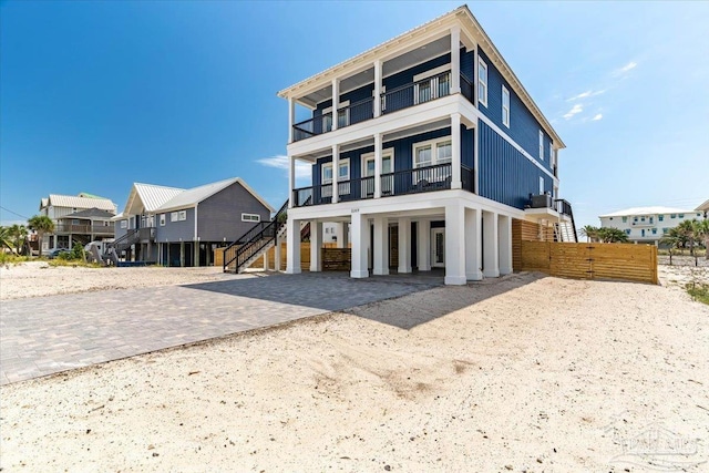8169 White Sands Blvd, Navarre Beach, FL 32566 - view of front facade featuring a balcony, a carport, dirt driveway, and stairs