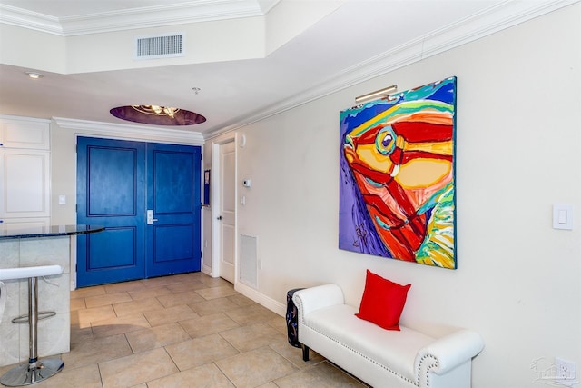 tiled foyer entrance with crown molding and a raised ceiling