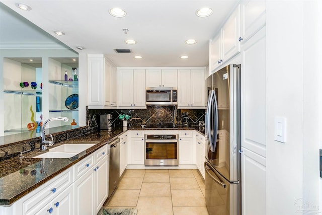 kitchen featuring light tile patterned flooring, white cabinets, sink, dark stone countertops, and appliances with stainless steel finishes