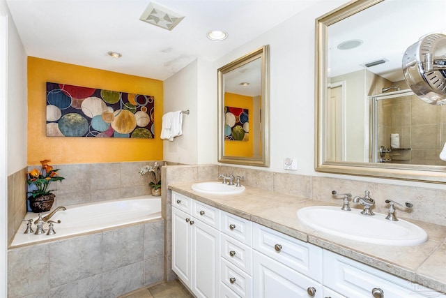 bathroom featuring dual vanity, tile patterned flooring, and a relaxing tiled tub