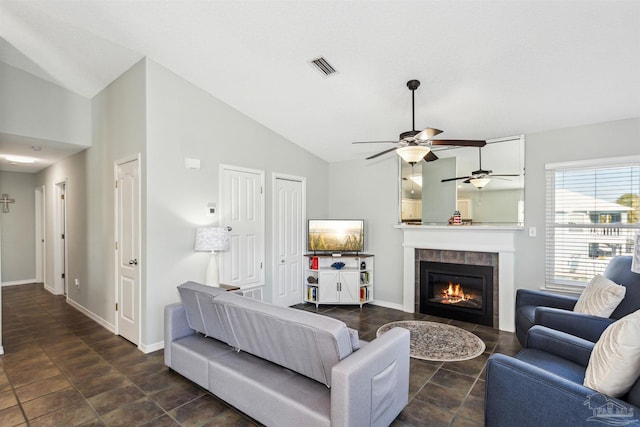 living room featuring vaulted ceiling, ceiling fan, and a tiled fireplace