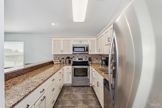 kitchen featuring white cabinets, appliances with stainless steel finishes, backsplash, and stone countertops