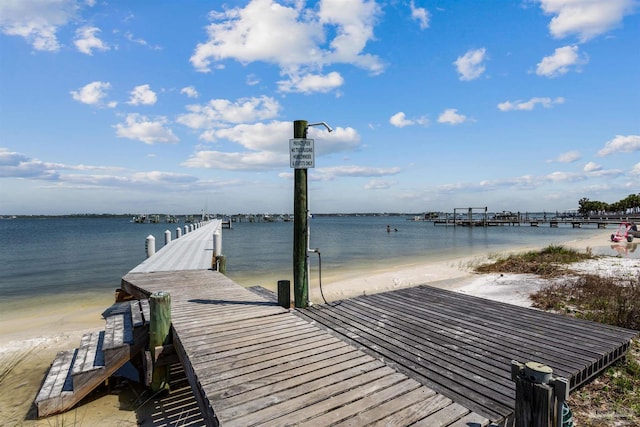 view of dock featuring a beach view and a water view