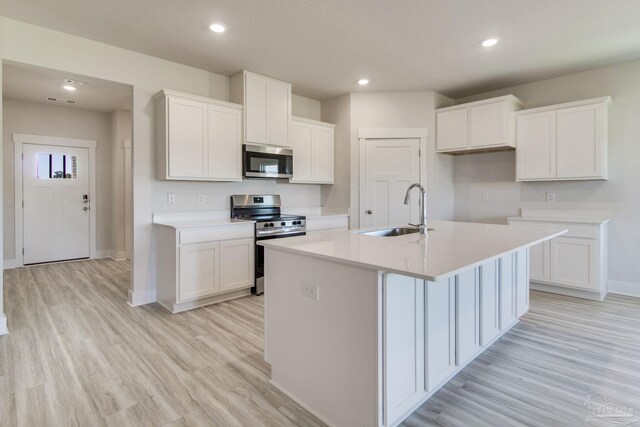 9797 Windyhill Rd, Pensacola, FL 32526 - kitchen with stainless steel appliances, a sink, baseboards, light wood-style floors, and white cabinets
