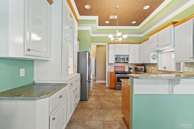 kitchen featuring white cabinets, kitchen peninsula, appliances with stainless steel finishes, decorative light fixtures, and ornamental molding