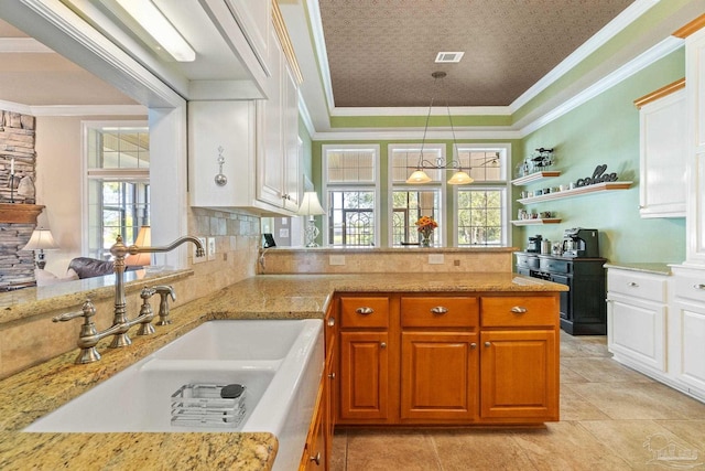 kitchen featuring kitchen peninsula, sink, pendant lighting, and white cabinets