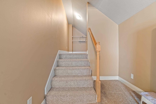 staircase featuring vaulted ceiling, a textured ceiling, and carpet floors