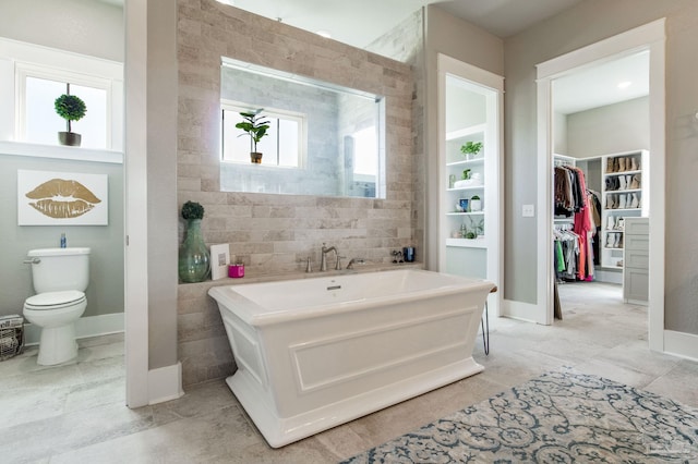 2420 Meeting St, Cantonment, FL 32533 - bathroom featuring baseboards, toilet, a walk in closet, a freestanding bath, and tile walls