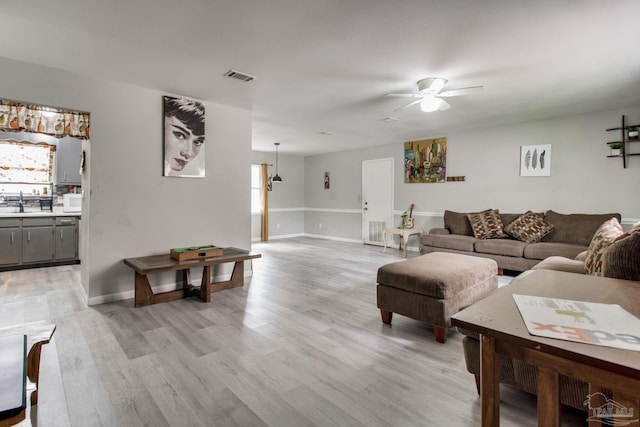 living area featuring visible vents, ceiling fan, baseboards, and light wood-style floors