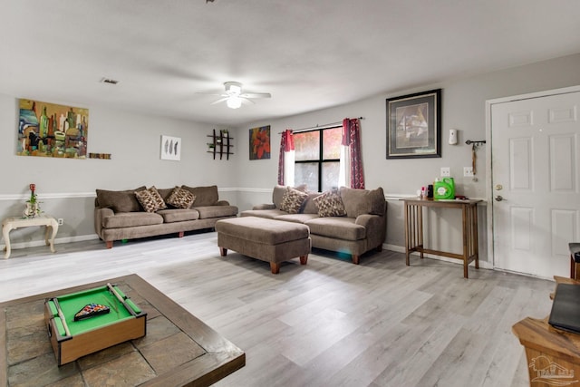 living area with visible vents, baseboards, light wood-style floors, and a ceiling fan