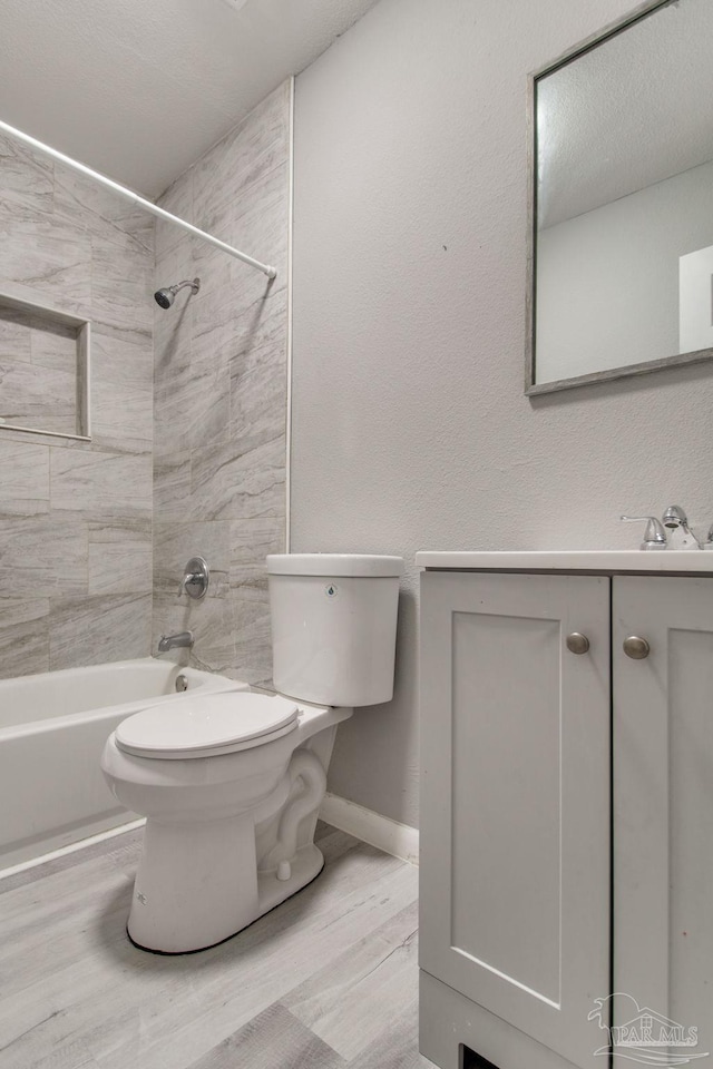 bathroom featuring toilet, shower / washtub combination, wood finished floors, baseboards, and vanity