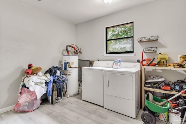 laundry area featuring washing machine and dryer, water heater, light wood-style floors, baseboards, and laundry area