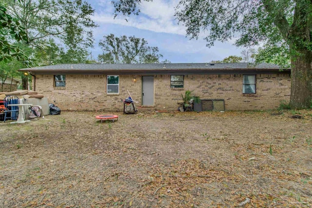 rear view of house featuring brick siding and an outdoor fire pit