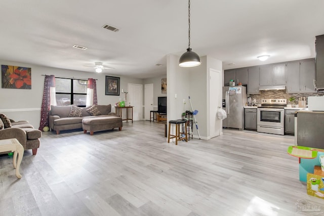 living room featuring visible vents, light wood-style flooring, and ceiling fan