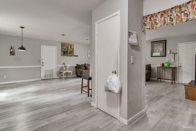 hallway with baseboards, visible vents, and light wood-type flooring