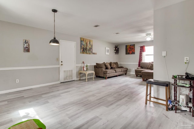 living area featuring visible vents, baseboards, wood finished floors, and a ceiling fan