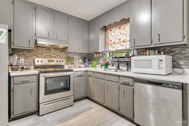 kitchen featuring under cabinet range hood, gray cabinets, appliances with stainless steel finishes, and a sink