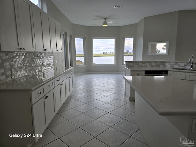 kitchen featuring decorative backsplash, light tile patterned floors, a kitchen island, and sink