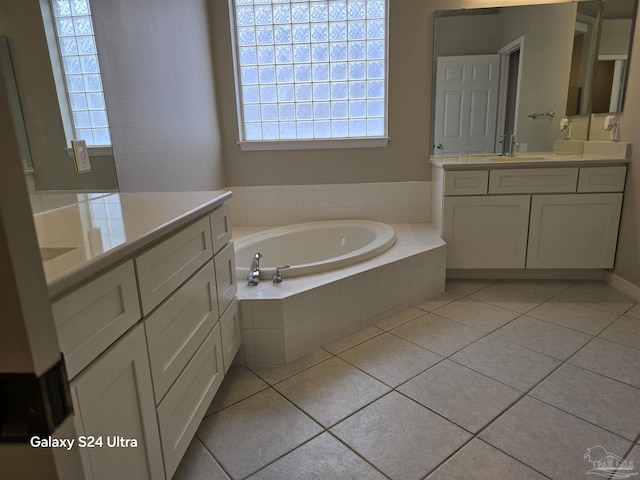 bathroom with tile patterned flooring, vanity, and a relaxing tiled tub