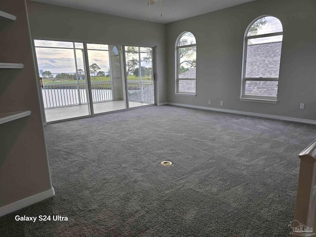 empty room with carpet flooring, ceiling fan, and a water view