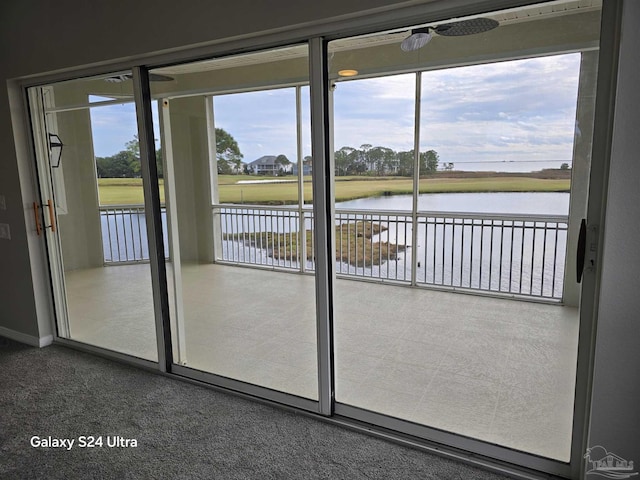 entryway featuring carpet flooring, a water view, a wealth of natural light, and ceiling fan