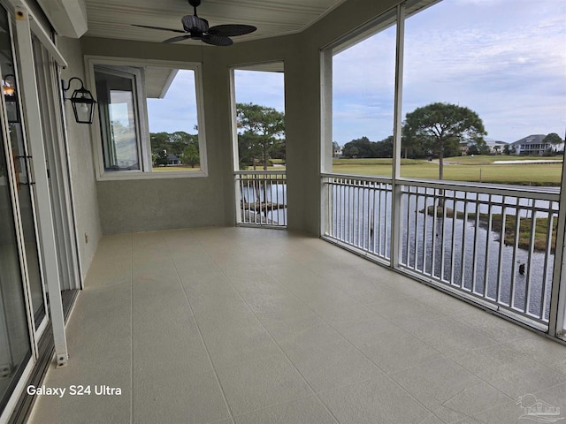 unfurnished sunroom featuring a water view and ceiling fan