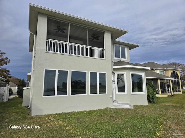 back of property featuring a lawn, a sunroom, and ceiling fan