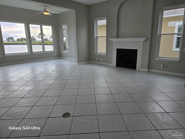 unfurnished living room featuring a tiled fireplace, ceiling fan, and light tile patterned floors