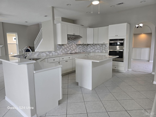 kitchen with white cabinetry, a kitchen island, tasteful backsplash, and sink