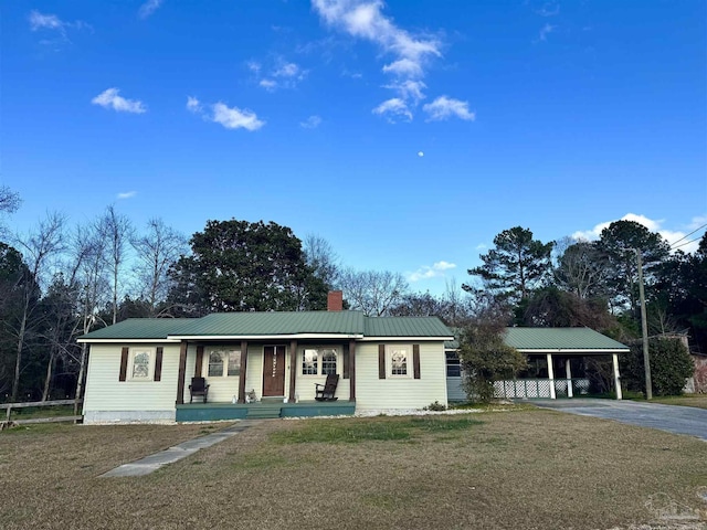 single story home featuring a carport, covered porch, and a front lawn