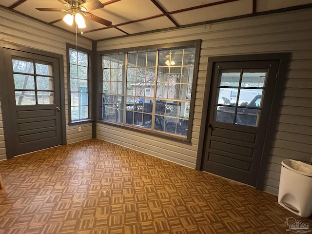 entryway featuring wooden walls and ceiling fan