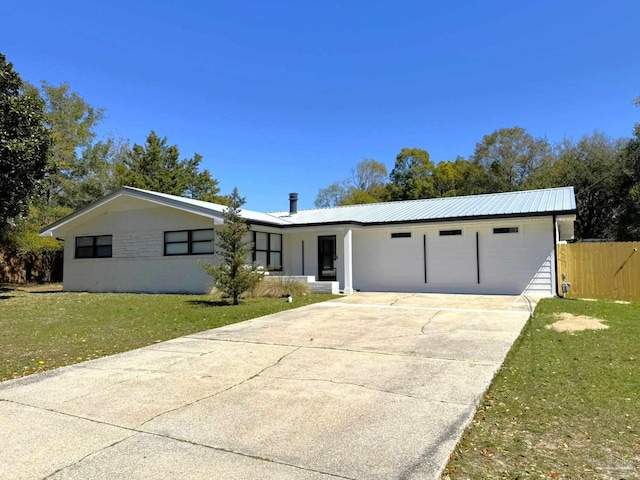 view of front of home featuring metal roof, a garage, fence, concrete driveway, and a front lawn