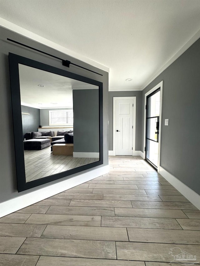 hallway featuring baseboards, ornamental molding, and wood finish floors
