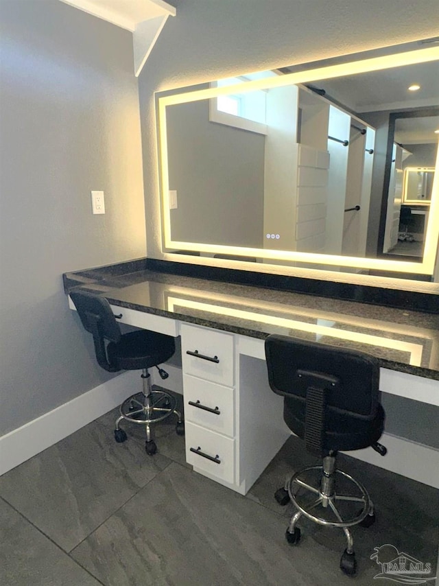 office area featuring marble finish floor, built in desk, and baseboards